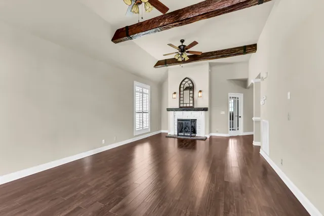 a view of an empty room with a fireplace and wooden floor