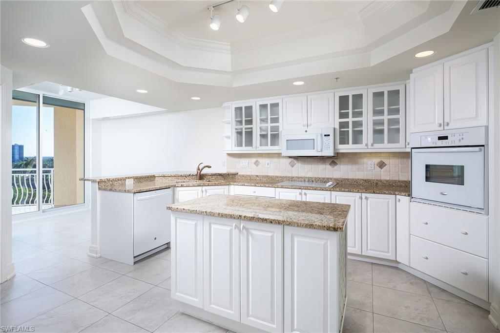435 Dockside Drive, Unit B703 Naples, FL 34110 - Photo 14 of 38 a kitchen with granite countertop white cabinets and white appliances