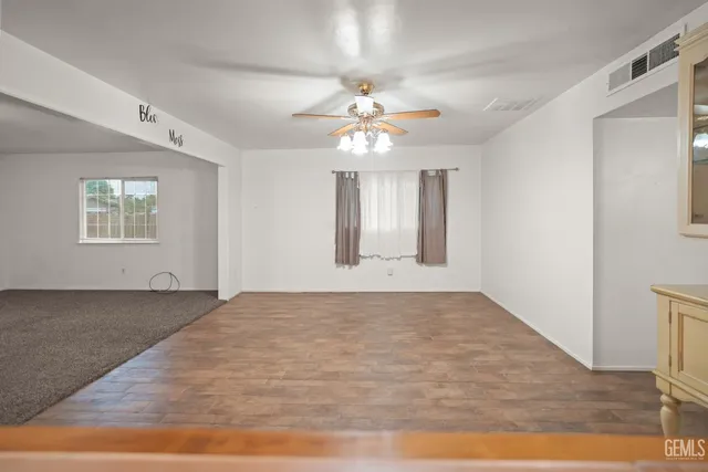 a view of an empty room with window and chandelier fan