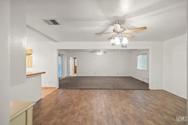 a view of an empty room with chandelier fan and window