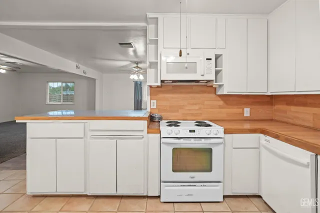 a kitchen with granite countertop white cabinets and white appliances