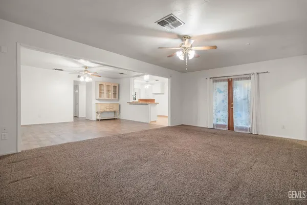 a view of an empty room with chandelier fan and windows
