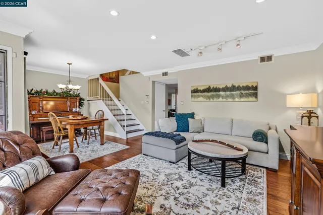 a living room with furniture and a dining table with rug couches