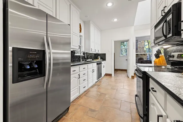 a kitchen with stainless steel appliances granite countertop a refrigerator a stove and a sink