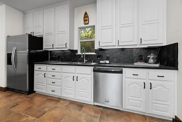 a kitchen with granite countertop white cabinets and stainless steel appliances