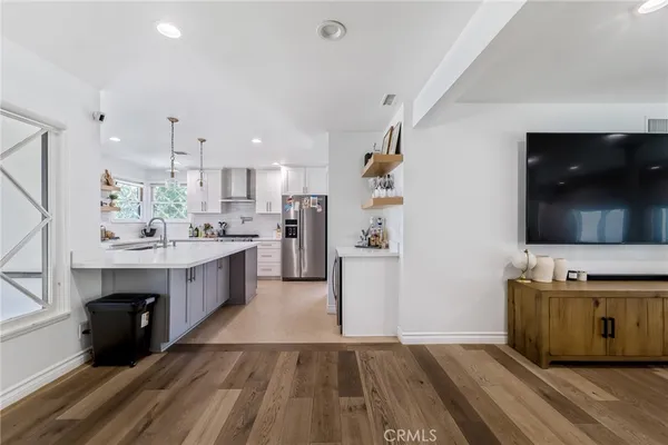 a kitchen with kitchen island a sink dishwasher a stove and a refrigerator with wooden floor