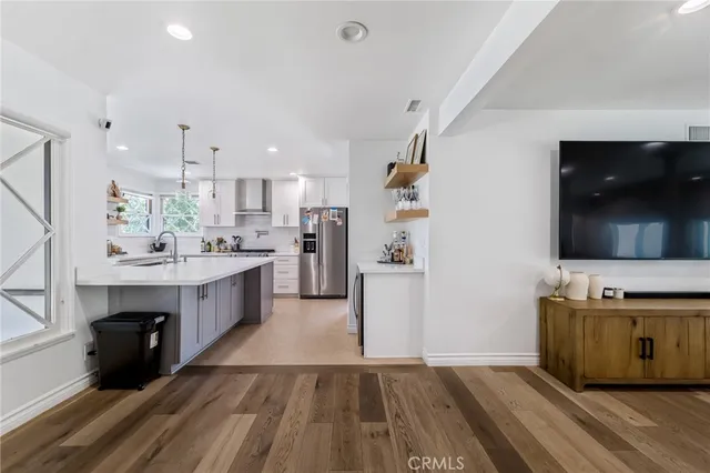 a kitchen with kitchen island a sink dishwasher a stove and a refrigerator with wooden floor