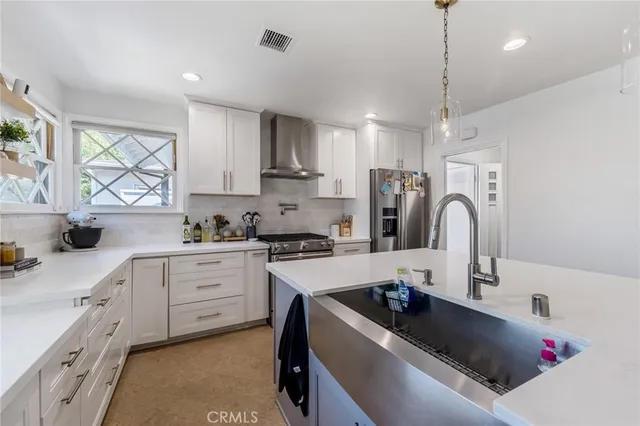 a kitchen with kitchen island white cabinets a sink a stove and a window