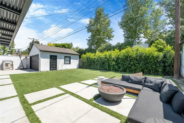 a view of a backyard with table and chairs potted plants and large tree