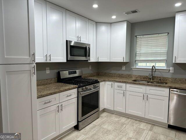 4889 Thompson Mill Road Stonecrest, GA 30038 - Photo 1 of 1 a kitchen with granite countertop white cabinets sink and stainless steel appliances