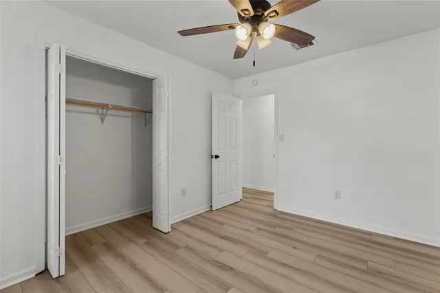 an empty room with wooden floor closet and fan with wooden floor
