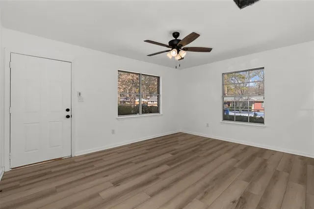 a view of empty room with wooden floor and fan