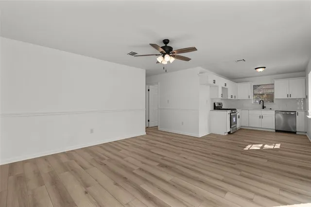 a view of a big room with wooden floor and a kitchen view