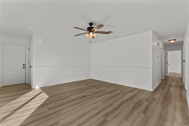 an empty room with wooden floor and fan