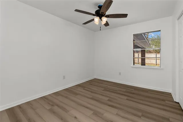 an empty room with wooden floor fan and windows