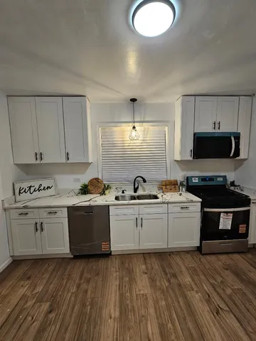 a kitchen with microwave a stove and cabinets