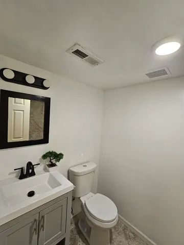 a bathroom with a toilet a sink and mirror