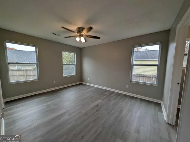 a view of an empty room with a window and wooden floor