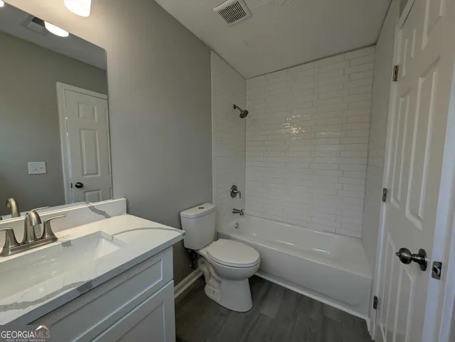a bathroom with a granite countertop sink a toilet and shower