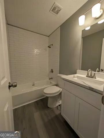 a bathroom with a granite countertop sink toilet a mirror and shower