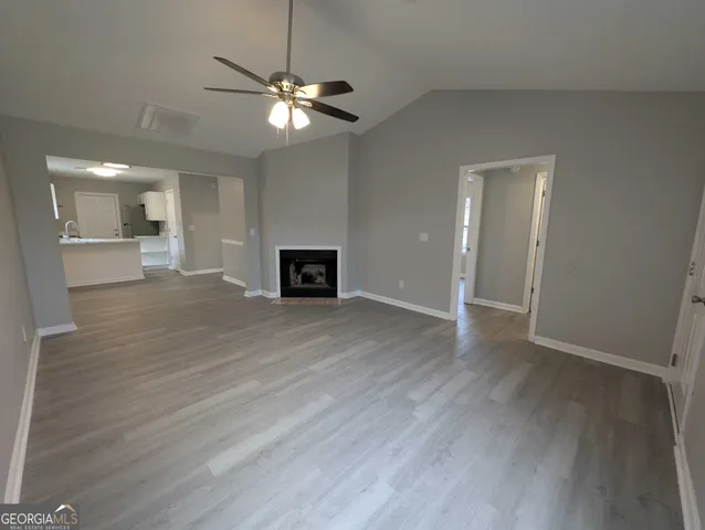 a view of a livingroom with a fireplace a ceiling fan and wooden floor