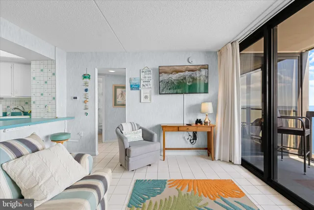 a living room with white couches and a kitchen view with wooden floor