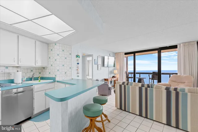 a kitchen with stainless steel appliances a white refrigerator a sink a stove a dining table and chairs