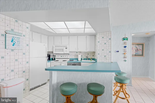 a kitchen with stainless steel appliances granite countertop a sink a stove a refrigerator and white cabinets with wooden floor