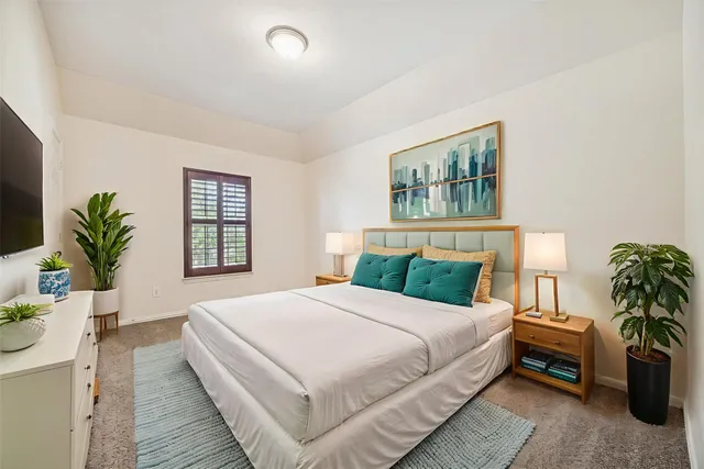 a bedroom with a large bed and a potted plant