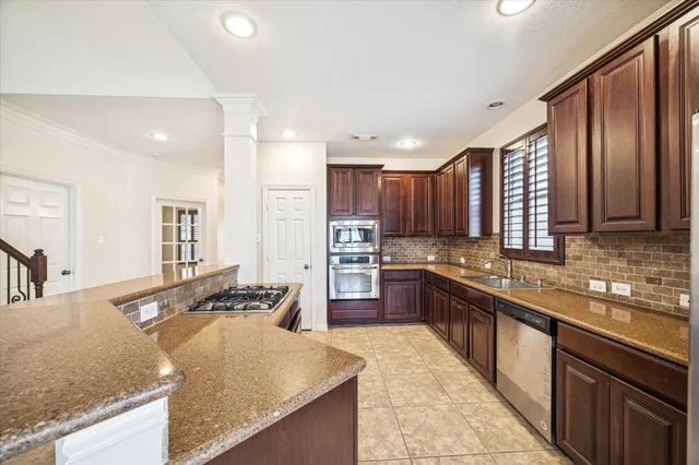 a large kitchen with stainless steel appliances granite countertop a sink stove and refrigerator