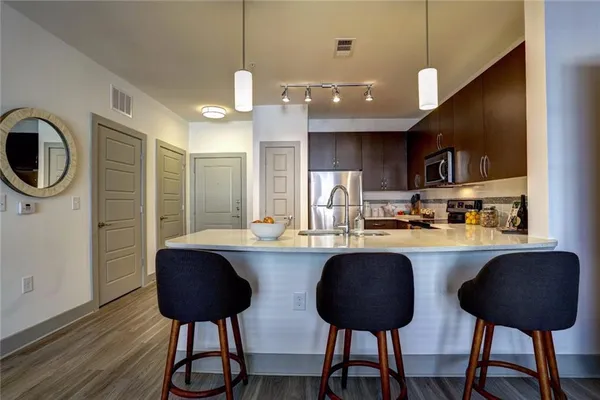a kitchen with stainless steel appliances granite countertop a sink a stove a refrigerator and chairs