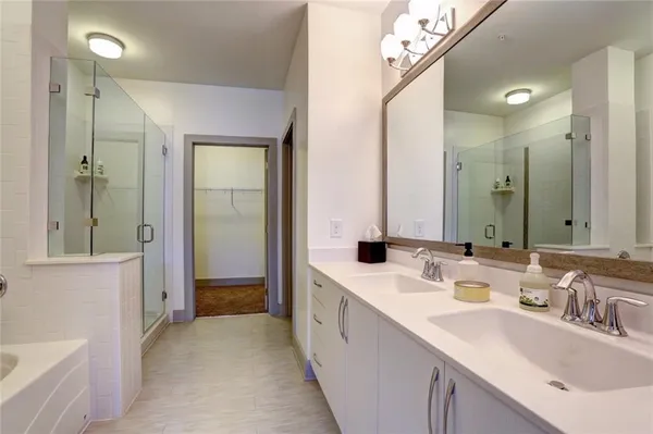 a bathroom with a double vanity sink mirror and bathtub