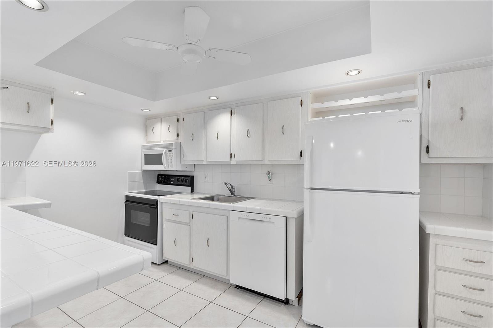 9273 Collins Avenue, Unit 901 Surfside, FL 33154 - Photo 4 of 24 a kitchen with white cabinets and white appliances
