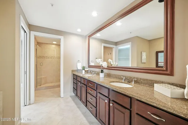 a bathroom with a granite countertop double vanity sink and a mirror