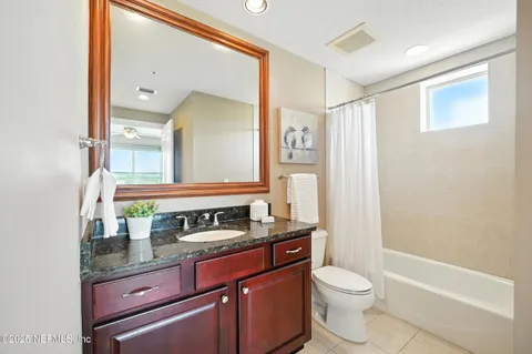 a bathroom with a granite countertop toilet sink and mirror