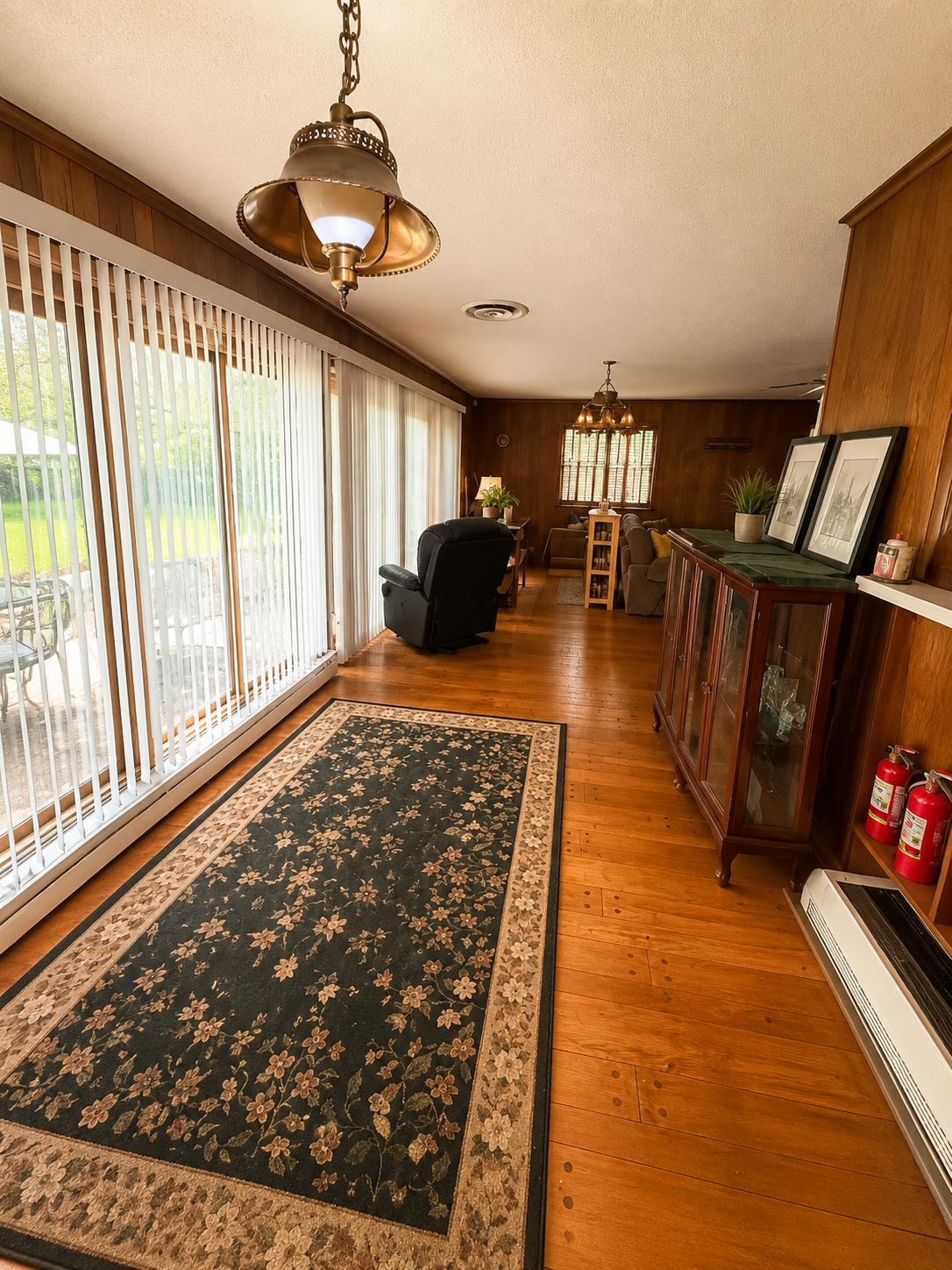 7280 Walsh Road Millington, TN 38053 - Photo 6 of 34 Expansive living area featuring wood-finish flooring, full-height sliding glass doors with vertical blinds, and paneling accents