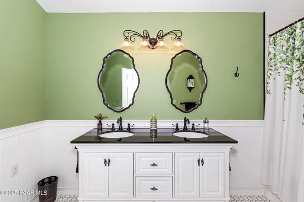 a bathroom with a double vanity sink a large mirror and a bathtub