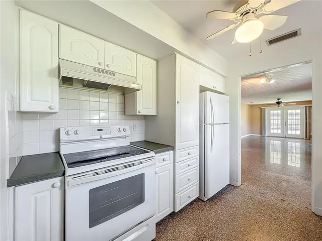 a kitchen with a sink dishwasher a stove and white cabinets