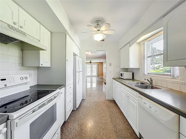 a kitchen with a sink dishwasher a refrigerator and white cabinets