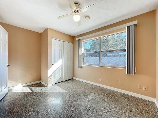 an empty room with windows and ceiling fan