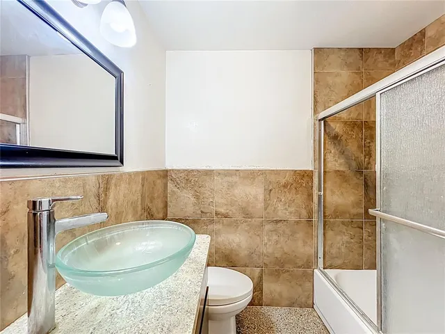 a bathroom with a granite countertop toilet sink and mirror