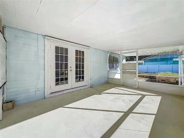 a view of an empty room with wooden floor and windows