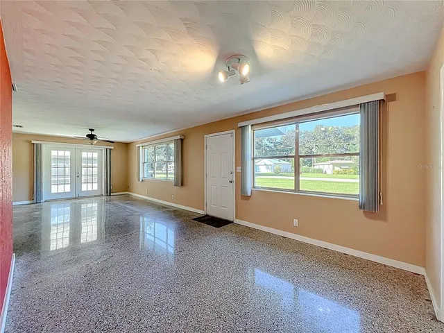 a view of an empty room with glass door and windows