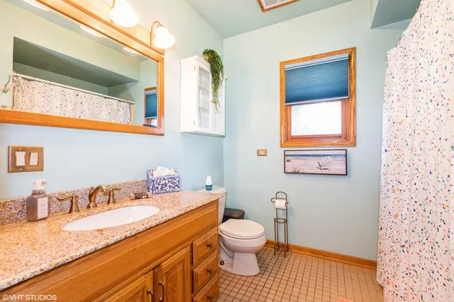 a bathroom with a granite countertop sink mirror vanity and toilet