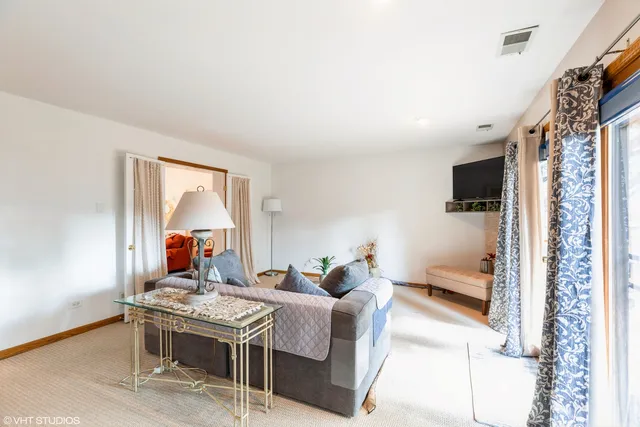a living room with furniture a flat screen tv and floor to ceiling window