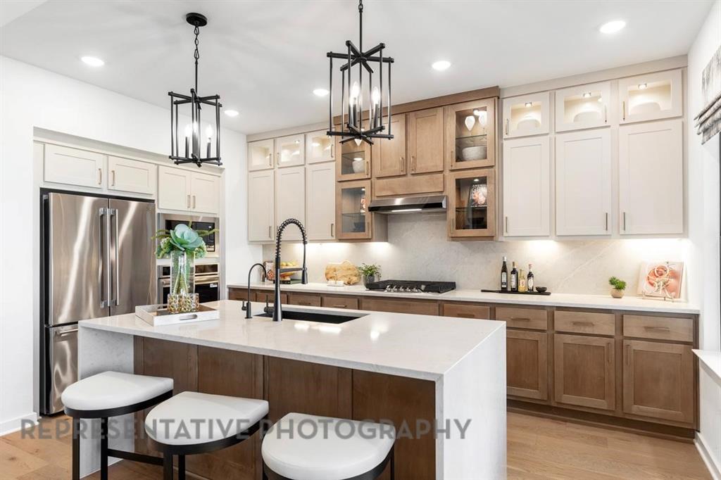 a kitchen with stainless steel appliances a sink a stove a refrigerator cabinets and chairs