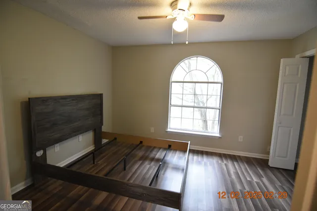 an empty room with wooden floor fan and windows