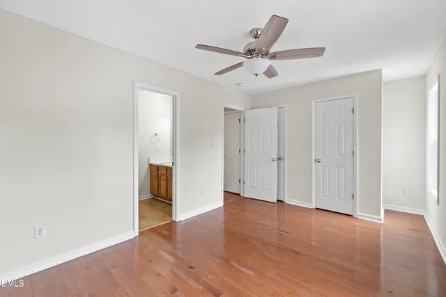 an empty room with wooden floor fan and windows