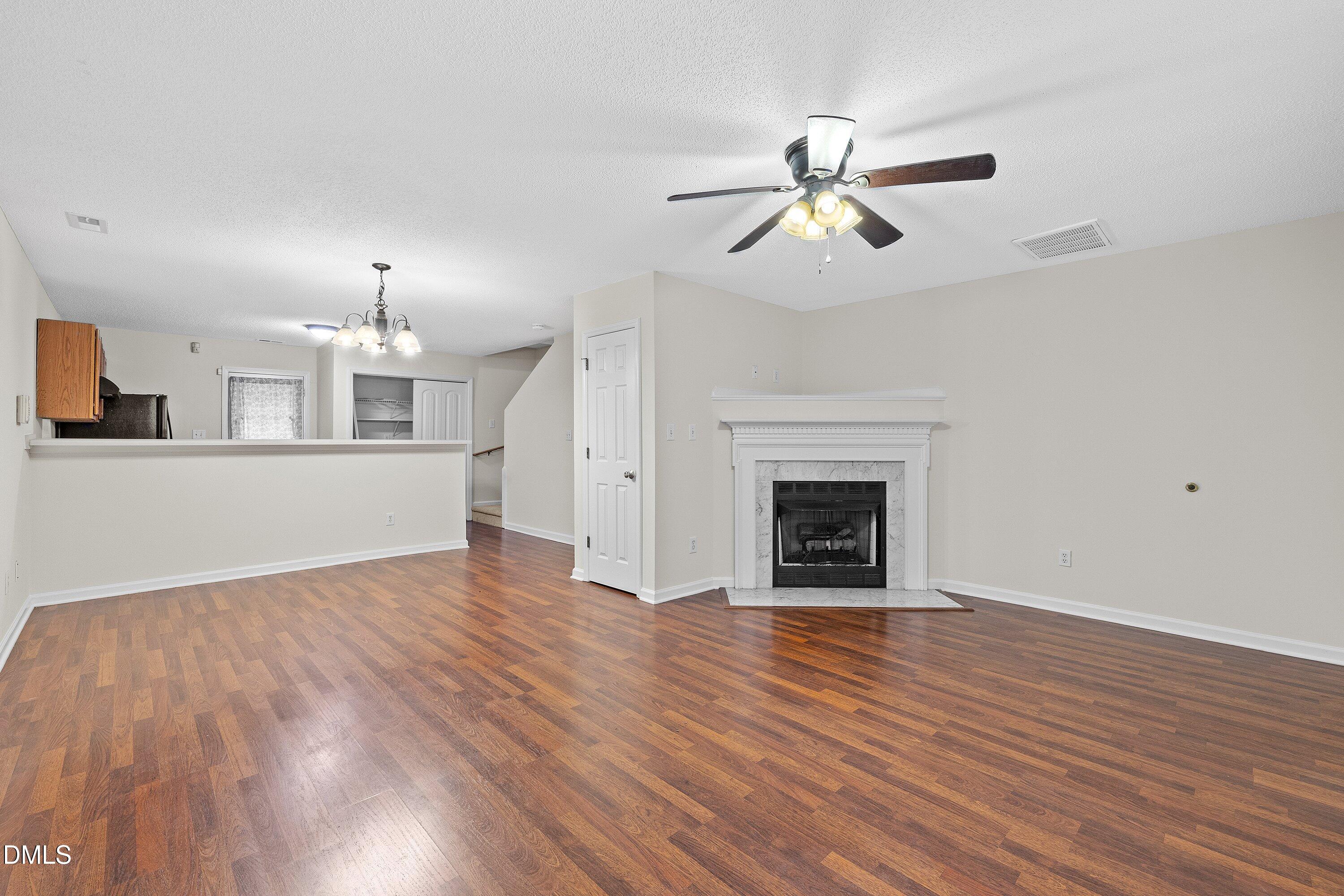 2241 Violet Bluff Court Raleigh, NC 27610 - Photo 4 of 28 an empty room with wooden floor a ceiling fan a fireplace and windows