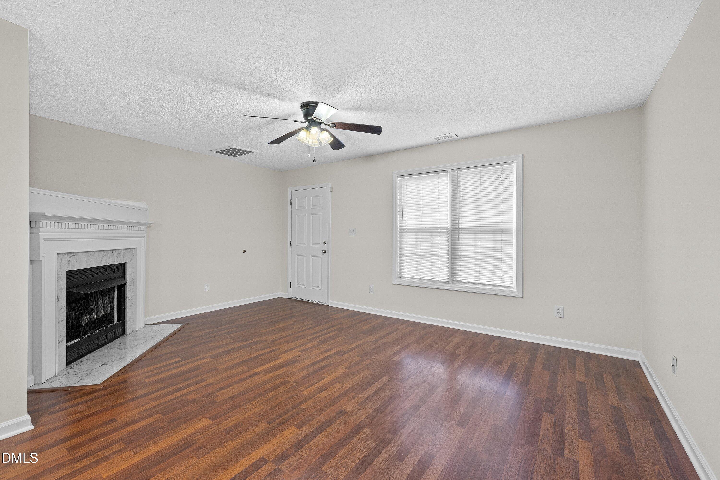 2241 Violet Bluff Court Raleigh, NC 27610 - Photo 5 of 28 a view of an empty room with wooden floor fireplace and a window